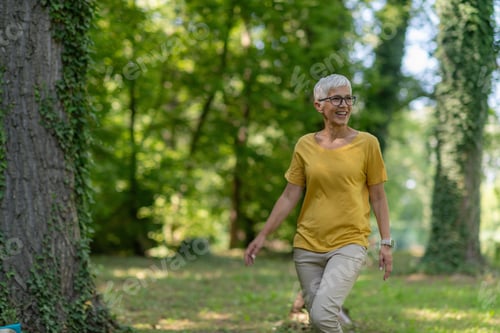 Preview: Senior woman enjoying a leisurely walk in the park for health and relaxation.