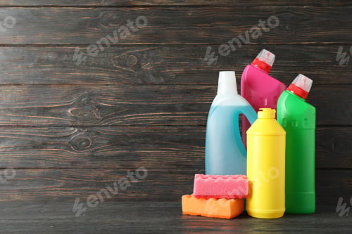 Preview: Bottles with detergent and sponges on wooden background, space for text