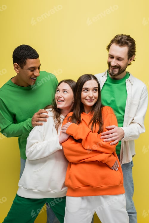 Preview: Positive women looking at interracial friends on yellow background