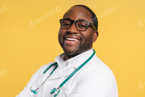 Preview: Happy African American doctor in glasses with stethoscope looking at camera in studio