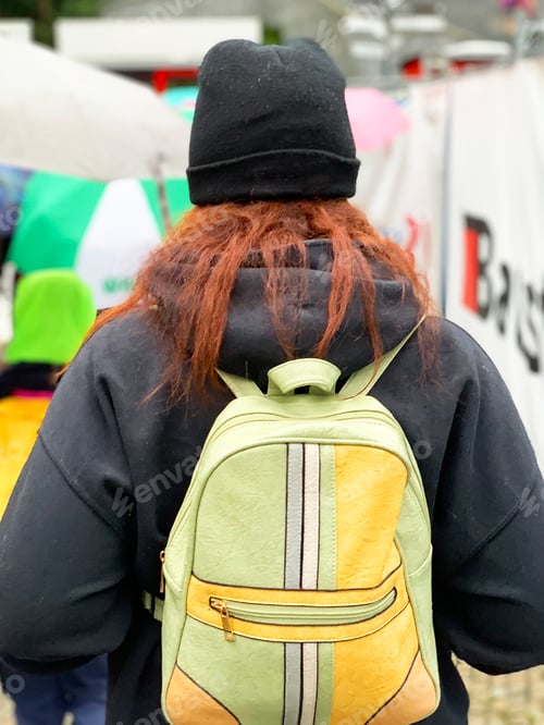 Preview: Unrecognizable Person Wearing Black Coat and Backpack With Pastel Green And Yellow Geometric Pattern