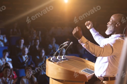 Preview: Businessman standing near podium and giving speech to the audience in the auditorium