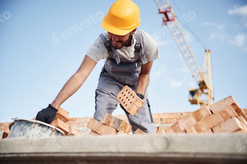 Preview: Blue sky and crane is behind. Handsome Indian man is on the construction site