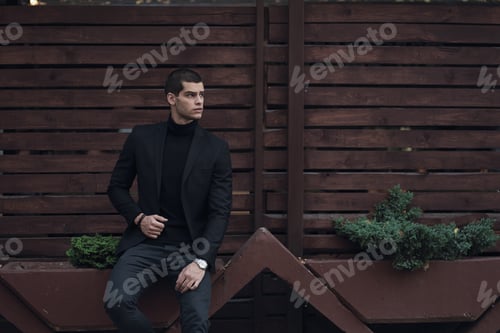 Stylish Man Leans Against Wooden Fence in City
