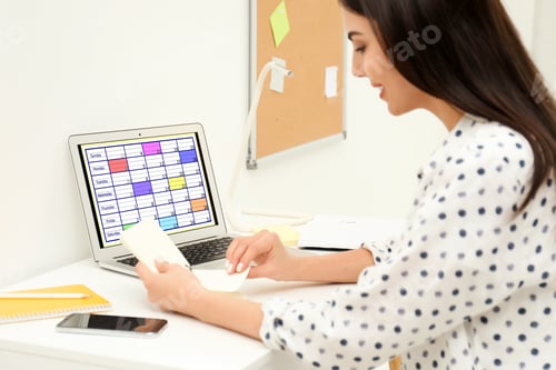Preview: Young woman planning her schedule with calendar app on laptop in office