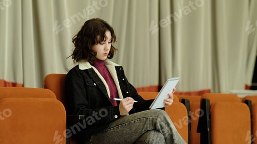 Preview: A thoughtful girl writes in a notebook while seated in a quiet auditorium. This image symbolizes