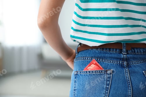 Preview: Woman with condom in pocket of her jeans indoors, closeup. Safe sex concept