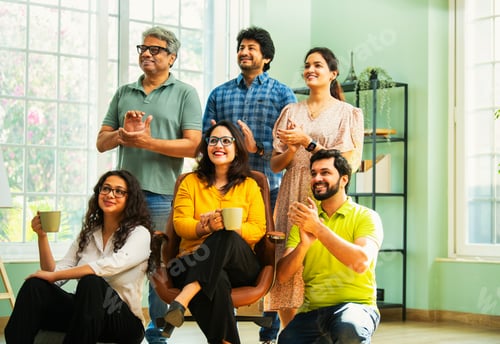 Preview: Young Indian Asian professionals in casuals clapping and looking up, celebrating success together