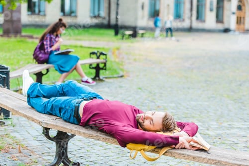 Preview: selective focus of student sleeping on wooden bench in park