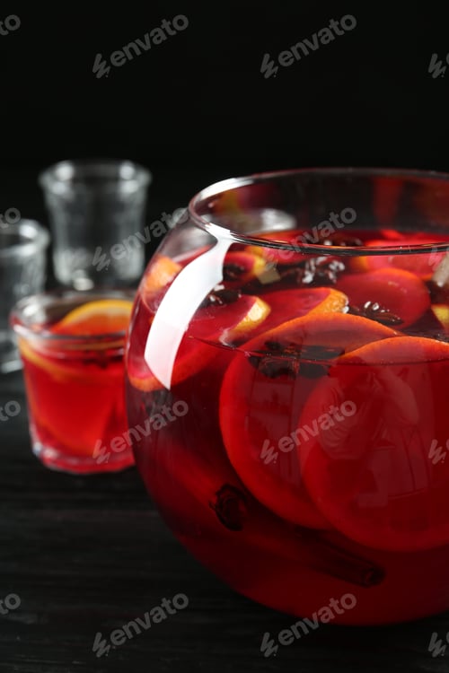Preview: Glass bowl of delicious aromatic punch drink on black wooden table, closeup