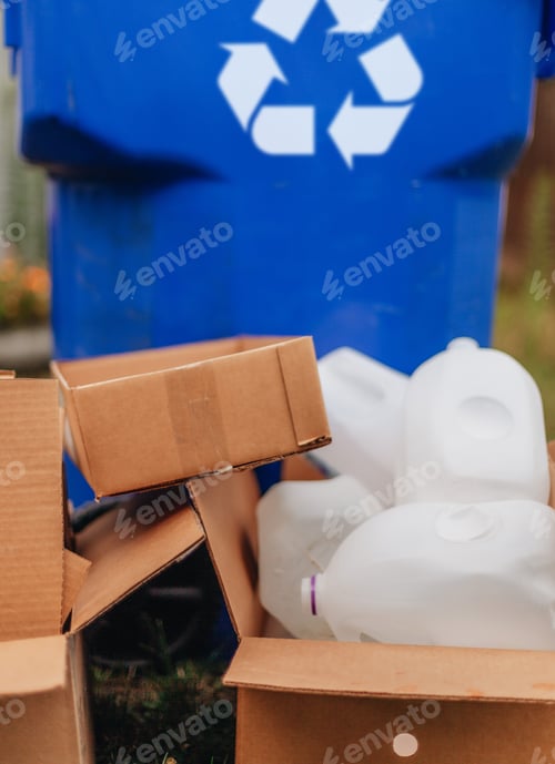 Vorschau: Stapel von Pappkartons und Plastikflaschen neben einem Papierkorb
