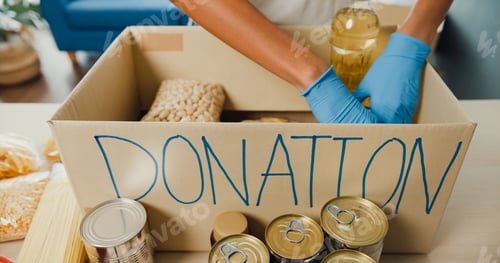 Preview: Young Asia teenage girl volunteer wear gloves packing food and drinks donation into donations.