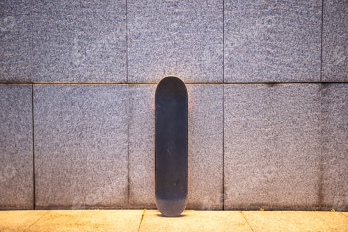 Preview: Skateboard against illuminated gray wall in city