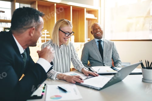 Preview: Three laughing businesspeople discussing paperwork together in an office