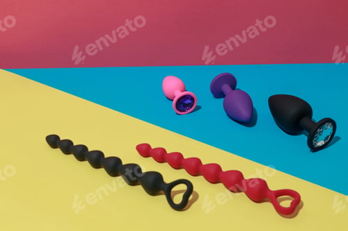Preview: Different buttplugs and dildos for anal sex on colored background with shadows. Sex shop concept
