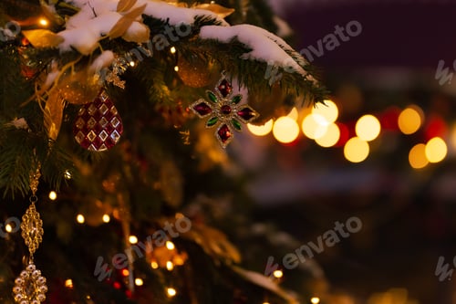 Preview: Christmas decor close-up on a Christmas tree, sprinkled with snow, in the evening on the street.