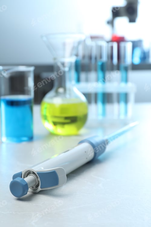 Preview: Laboratory analysis. Micropipette and different glassware with liquids on light grey marble table