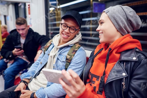 Preview: Young couple waiting in underground station looking at smartphone