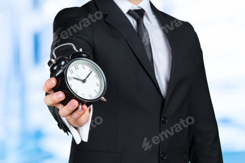 Preview: Unrecognizable businessman with an alarm clock in a hand