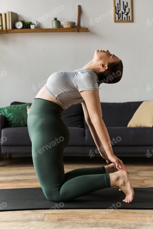 Preview: Young woman in stylish crop top and leggings engages in a home workout session on a yoga mat