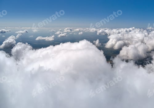 Preview: Aerial view from airplane window at high altitude of earth covered with white puffy cumulus clouds.