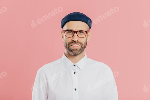 Preview: Headshot of satisfied bearded young man looks confidently at camera through spectacles
