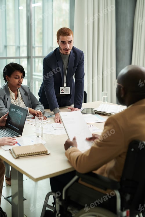 Preview: Focus on young businessman looking at male colleague in wheelchair