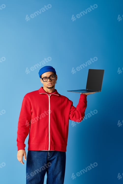 Preview: Stylish young african american man showing laptop against vibrant blue backdrop