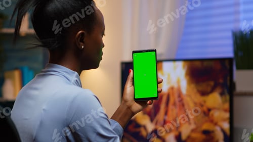 Preview: Lady looking at green screen smartphone while relaxing at home