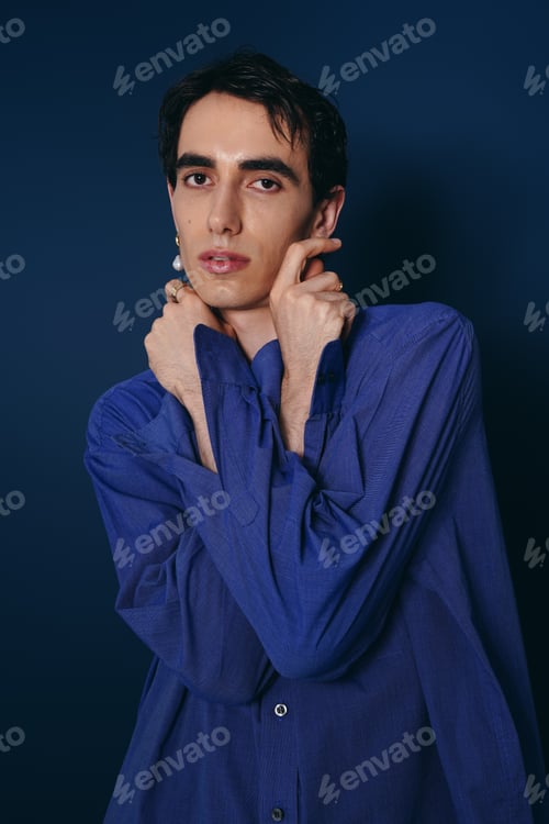 Preview: Handsome young man posing stylishly against a deep blue background in a trendy outfit