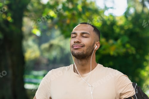 Preview: Close-up portrait of sportsman in park, hispanic man jogging in park with eyes closed breathing