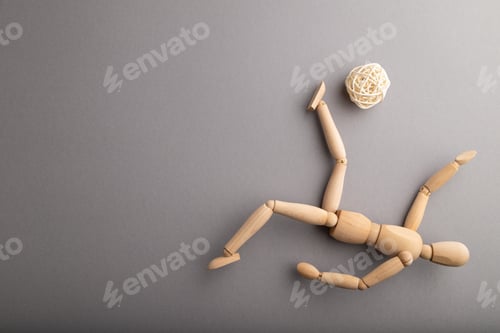 Preview: Wooden mannequin playing football on gray pastel background. copy space.