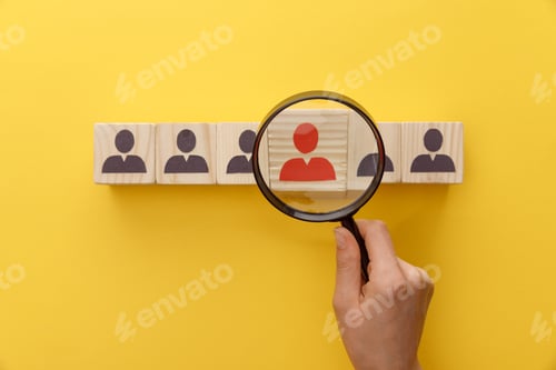 Preview: cropped view of woman holding magnifying glass under wooden cubes with logo on yellow background