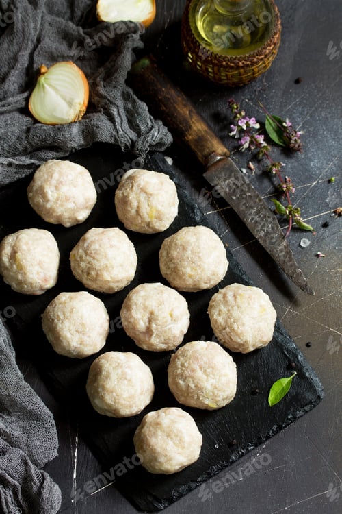Preview: Homemade turkey meatballs raw on slate blackboard.