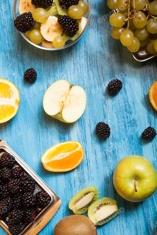 Preview: Top view of fruits and barries over a blue desk in studio