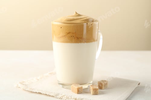 Preview: Delicious dalgona coffee in glass cup and brown sugar on light table, closeup
