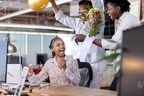 Preview: Surprising woman with flowers, African American colleagues celebrating success at office