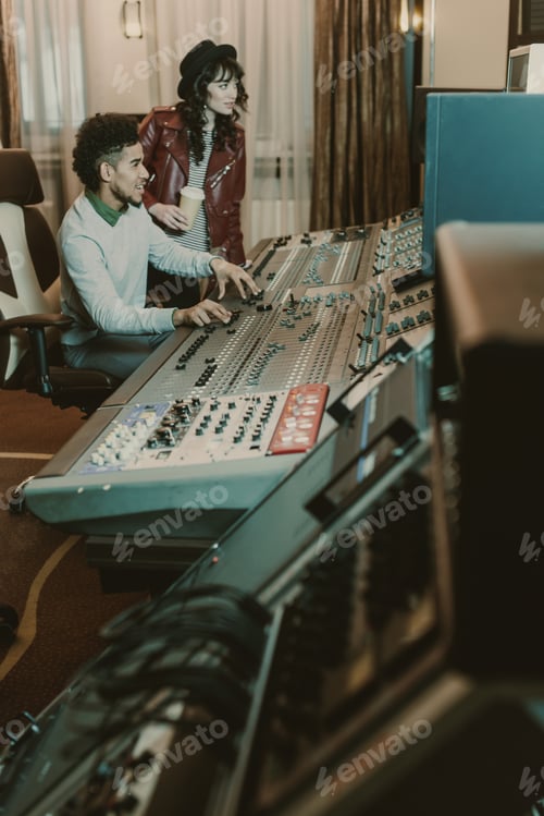 Preview: young successful musicians workign with equipment at recording studio