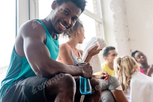 Preview: Selective focus of african american dancer holding sports bottle while smiling at camera in dance