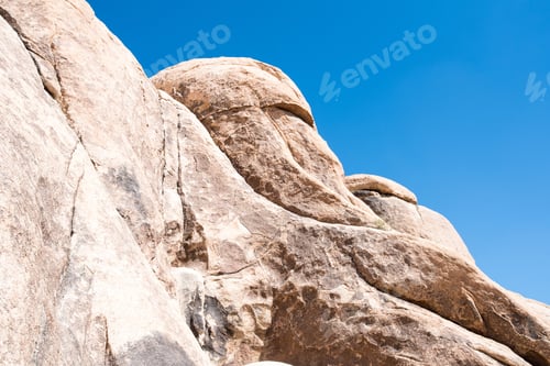 Preview: Giant rocks with cracks on them with a blue sky on the horizon