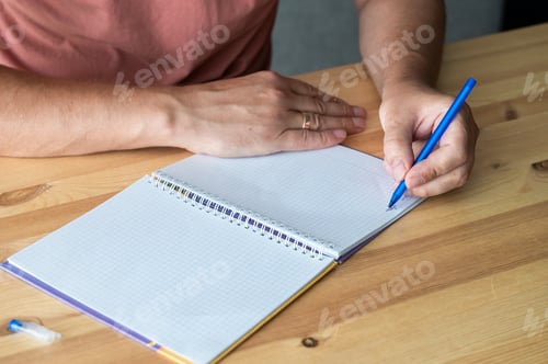 Preview: Man Writing in Notebook at Wooden Desk. International Dysgraphia Awareness Day (IDAD)