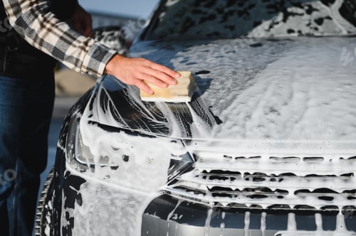 Preview: A man washes a car with a sponge at a self-service car wash