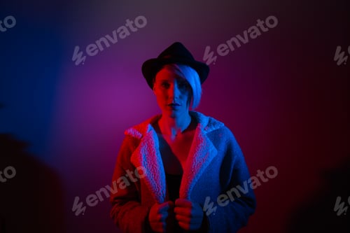 Preview: Attractive woman with hat shoot in studio with blue and red lights