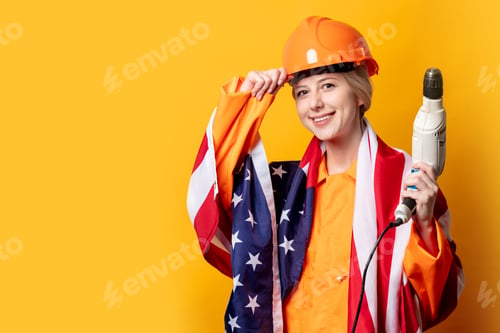 Preview: American woman in worker suit and helmet with USA flag and drill