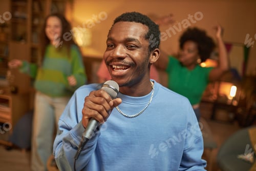 Preview: Black Man Singing to Microphone Enjoying Karaoke at Home Party with Friends