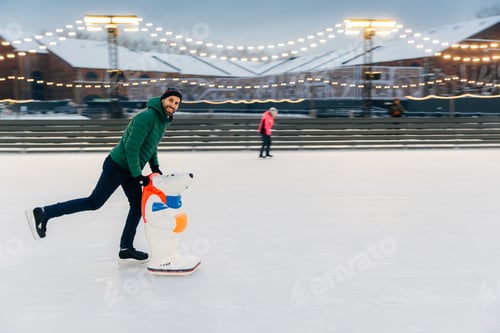 Preview: Happy middle aged male skater stands on ice ring, enjoys free time, has active lifestyle.