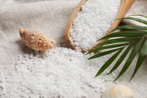 Preview: Scoop of natural sea salt, leaf and shell on cloth, closeup