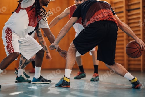 Preview: Cropped picture of interracial basketball players training on court.