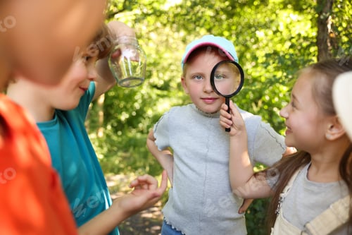 Preview: Group of children with magnifying glass in nature, selective focus