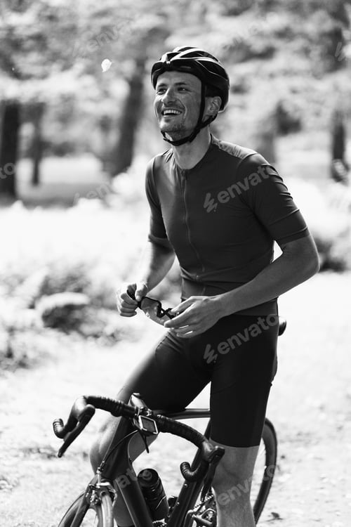 Preview: Sportsman sitting on bike and smiling sincerely outdoors